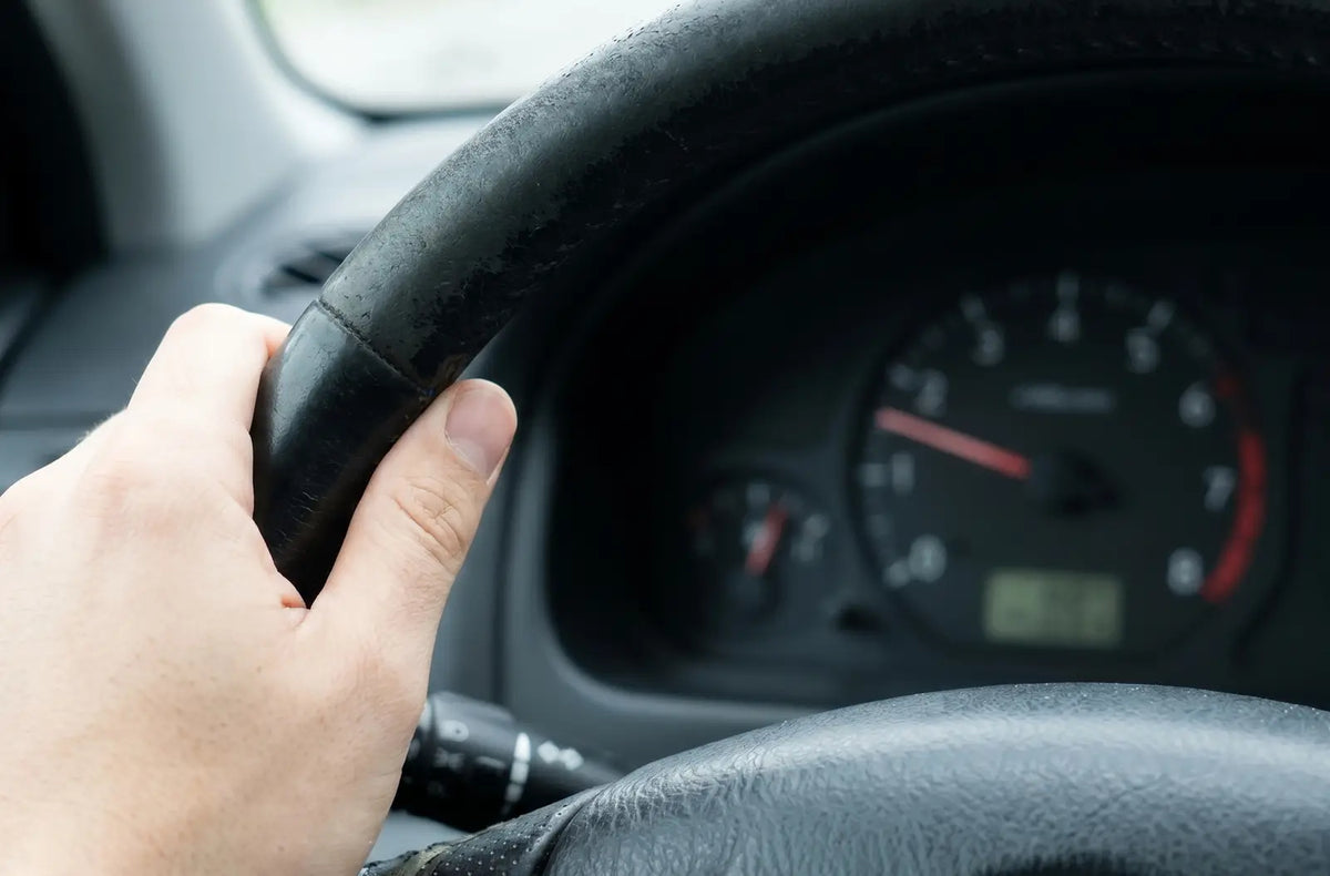 Close-up shot of a car's analog instrument panel showing a fluctuating engine tachometer gauge needle hovering near low RPM numbers.